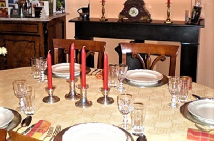 A dining table set with 5 place settings, crystal, and candles