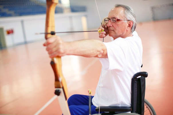 Older man in wheelchair practicing archery