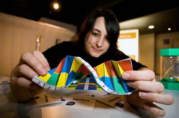 Woman folding colorful paper with her hands to make an origami object