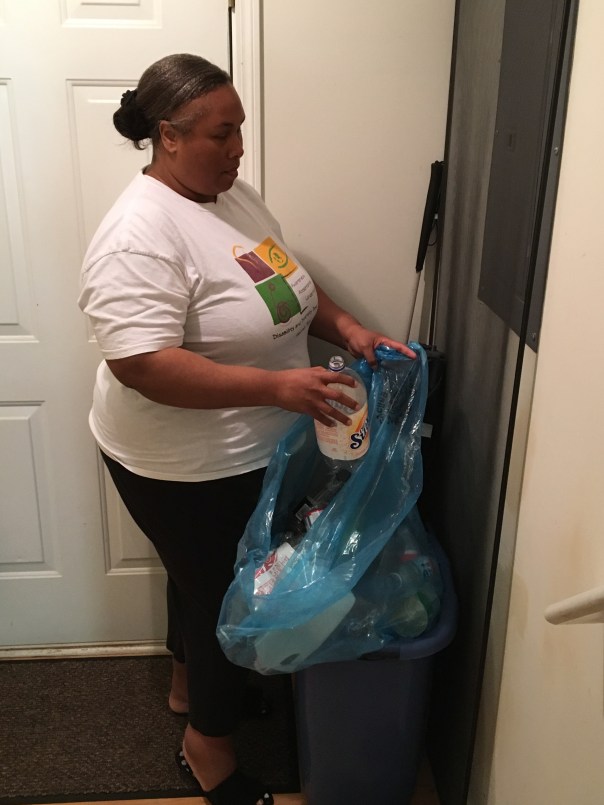 Empish placing items in blue recycle bag