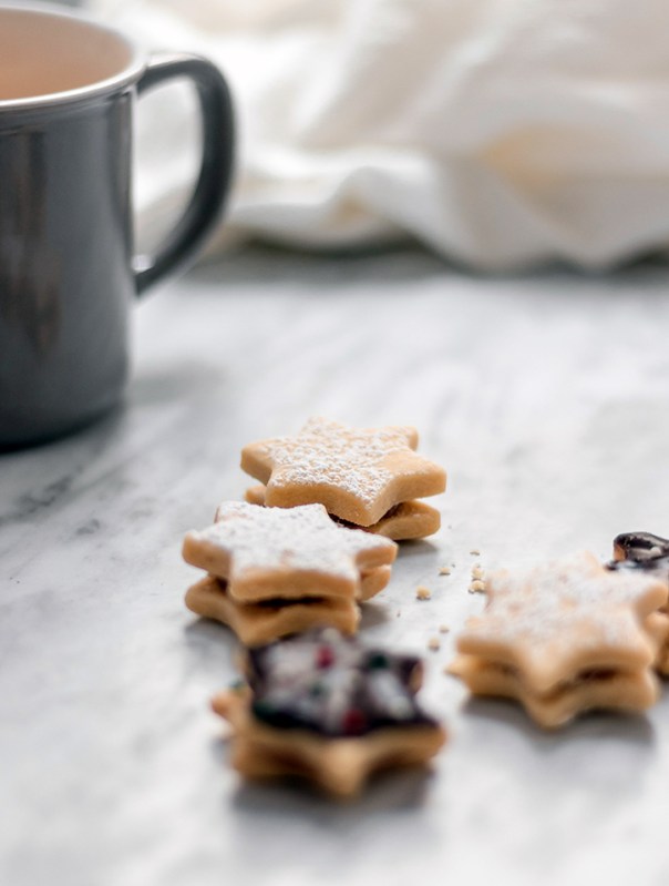 Star shaped powder sugar cookies on a plate with cup of coco