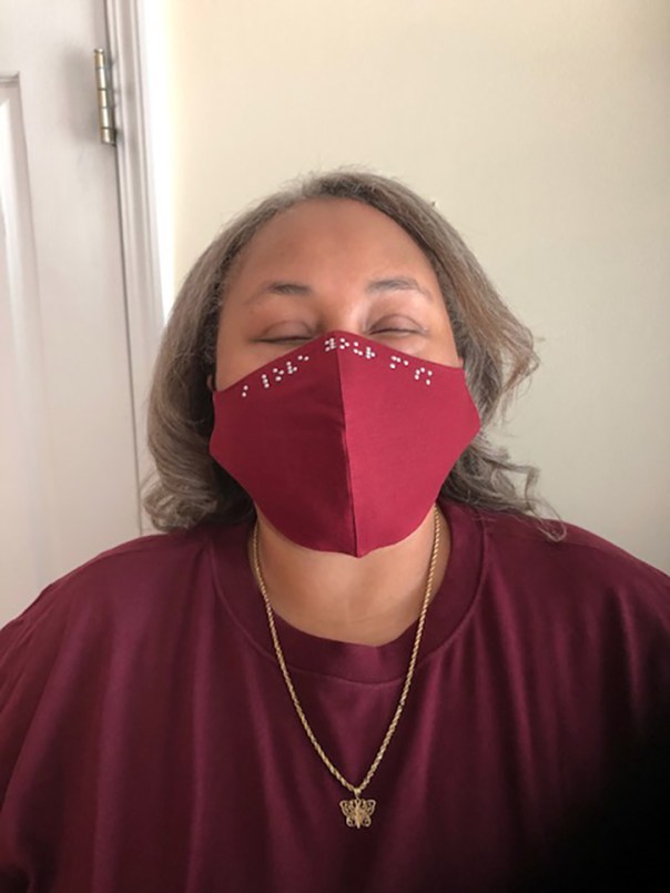 Empish wearing red top with matching red braille facemask