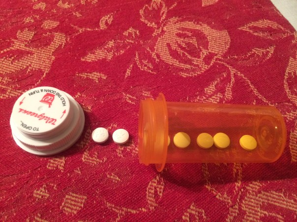 A prescription bottle laying on the side with medication spilling out.
