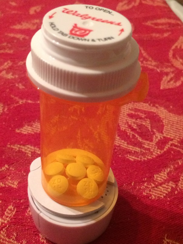 A prescription bottle with medication and a Pill Reminder attached to the top.