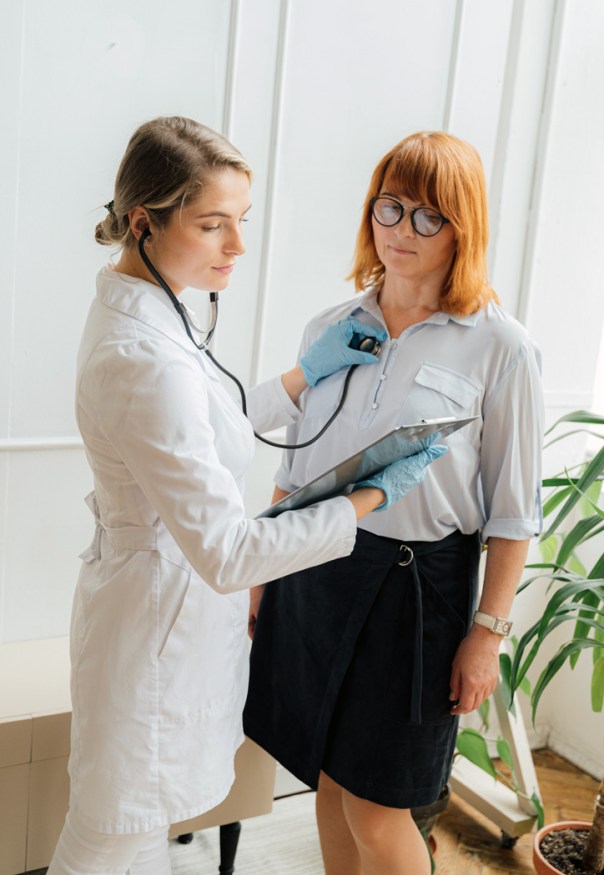 A female doctor listening to her female patient's heartbeat