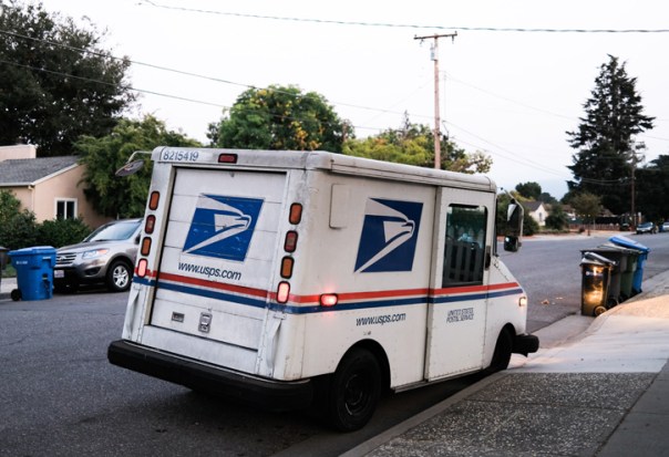 A mail truck parked on a street in a residential neighborhood.